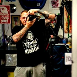 Tattooed Man Taking a Selfie in a Tattoo Shop